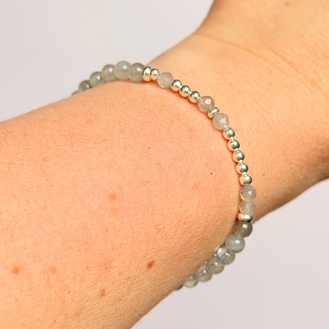 Elasticated labradorite crystal morse code bracelet that spells out the words ‘Let them’ in a combination of 4mm round labradorite beads, 4mm faceted labradorite beads and either sterling silver or gold vermeil 3mm round beads. The words start and end at the rondelle spacer beads.