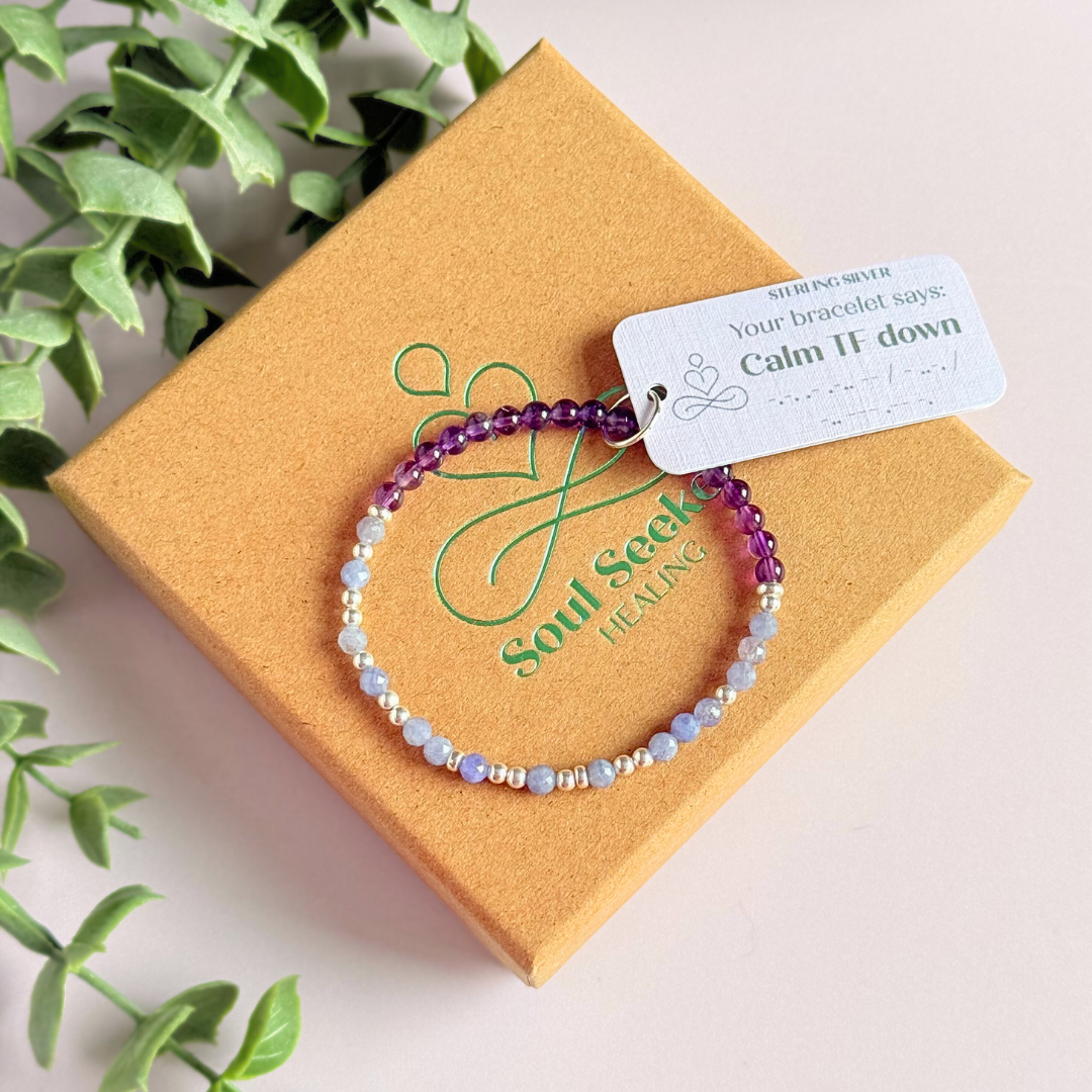 Amethyst and tanzanite elasticated stretch crystal morse code bracelet that spells out the words ‘Calm TF down’ in a combination of 4mm round amethyst beads, 4mm faceted tanzanite beads and either sterling silver or gold vermeil 3mm round beads. The words start and end at the rondelle spacer beads.