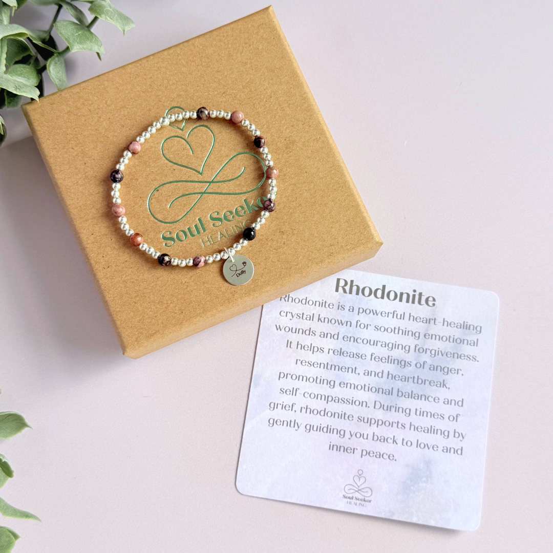 Sterling silver bracelet featuring ethically mined 4mm rhodonite crystal beads, separated by 3mm sterling silver beads. It features an 11mm sterling silver disc charm, which is engraved with a love heart and paw design, which can be personalised with your pet's name. The reverse of the charm says 'Forever in your heart x', although this side can also be personalised with your own words.