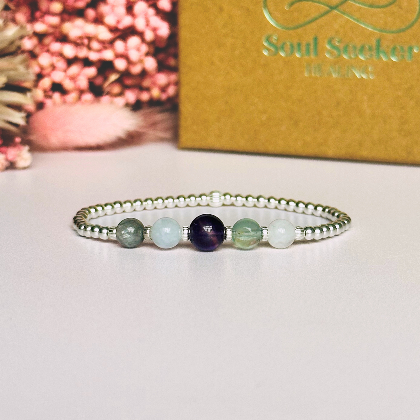 This sterling silver Aquarius bracelet is made with a selection of five healing crystals all believed to resonate with the Aquarius zodiac sign. The central bead is 8mm, the other four are 6mm. On an elasticated band of 3mm sterling silver beads with corrugated accent beads. Featuring labradorite, moonstone, fluorite, amethyst and aquamarine.
