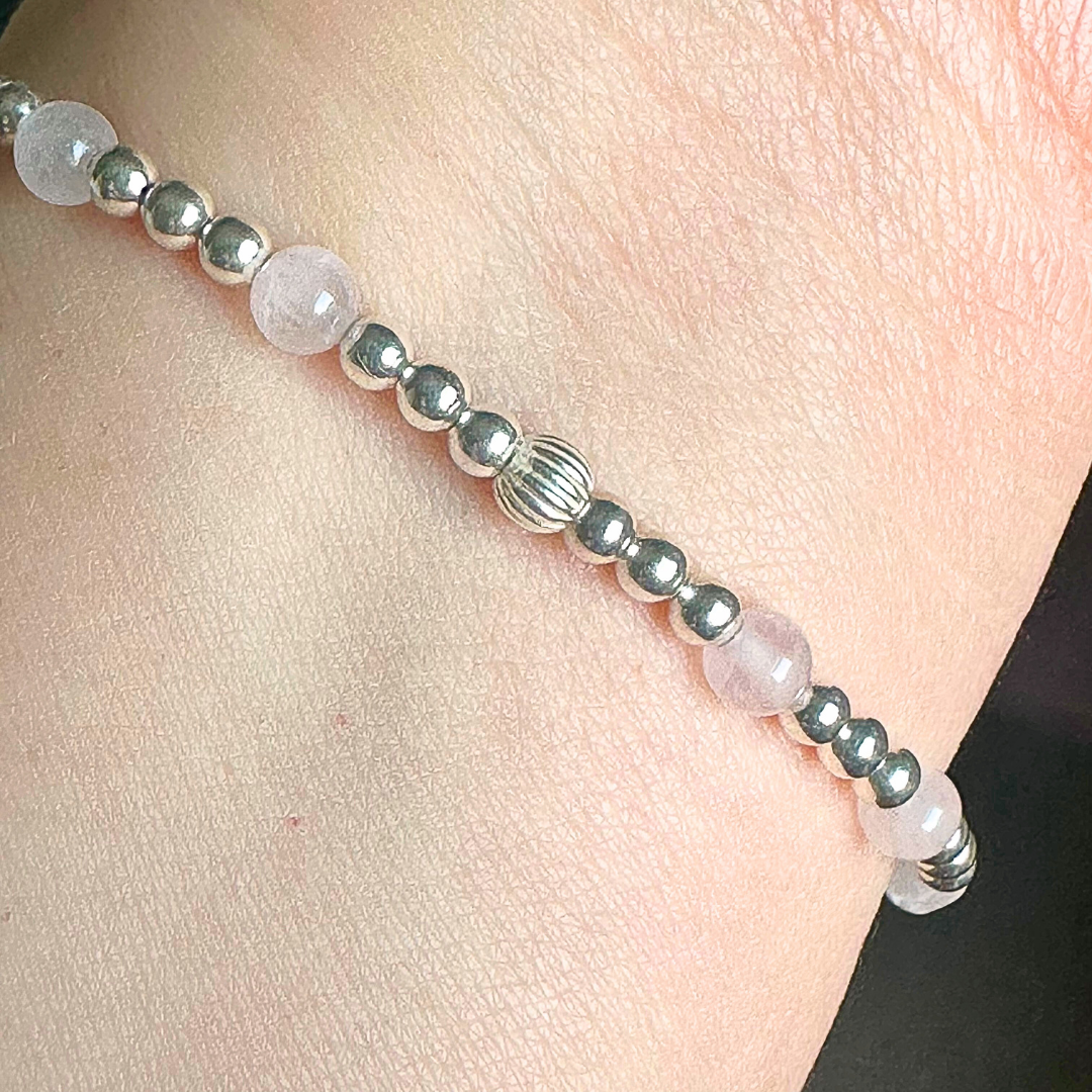 Sterling silver elasticated bracelet featuring 4mm round rose quartz beads, separated by 3mm sterling silver round ball beads. Featuring an 11mm sterling silver round disc charm engraved with the words love. One side of the charm can be personalised if required.
