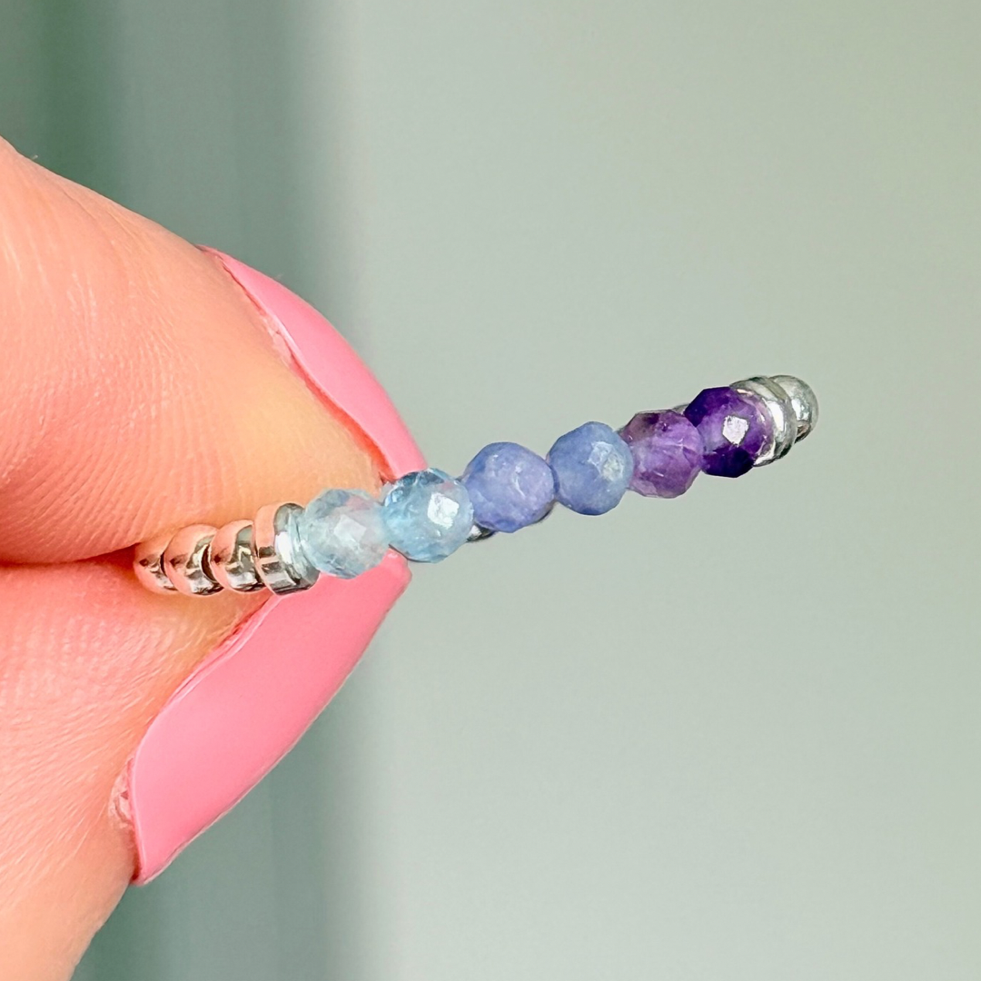 Sterling silver band style ombré ring with multicolour 3mm faceted amethyst tanzanite and aquamarine, beads with a beaded band of 2.5 mm sterling silver round beads. Elasticated for comfort.