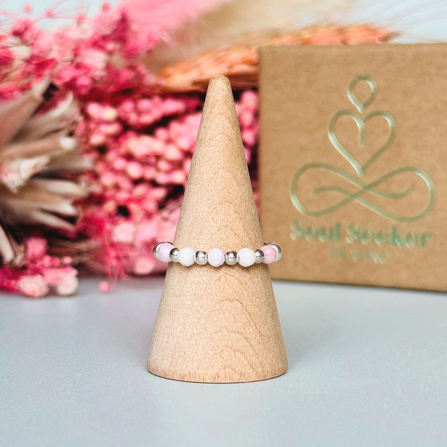 Birthstone ring featuring 5 3mm. Faceted Peruvian pink opal beads on an elasticated band of 3mm sterling silver round beads, pink opal is an October birth stone so this makes a perfect October birthday gift.