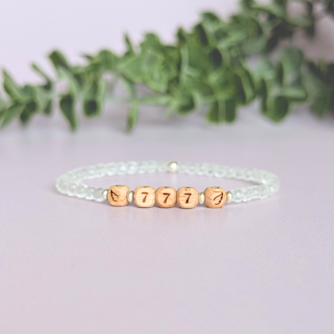 Bracelet featuring engraved wooden 777 angel number and wing beads, on the band of 4mm faceted clear quartz round crystal gemstone beads. Finished with your choice of gold vermeil, sterling silver or rose gold vermeil accent beads.
