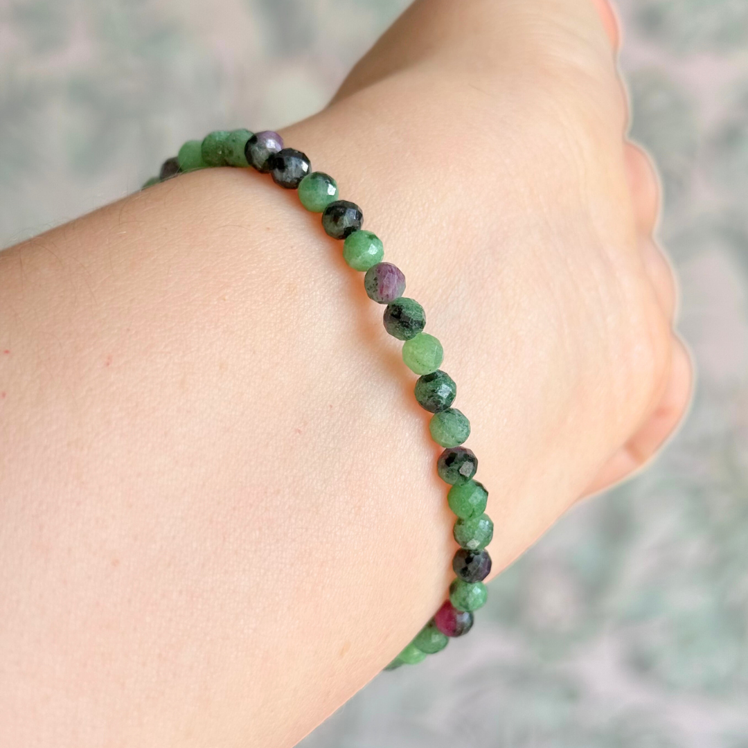 Essential oil diffuser bracelet featuring black lava rock tube bead on the band of 4mm faceted ruby in zoisite beads. Finished with your choice of sterling silver or gold vermeil accent beads.