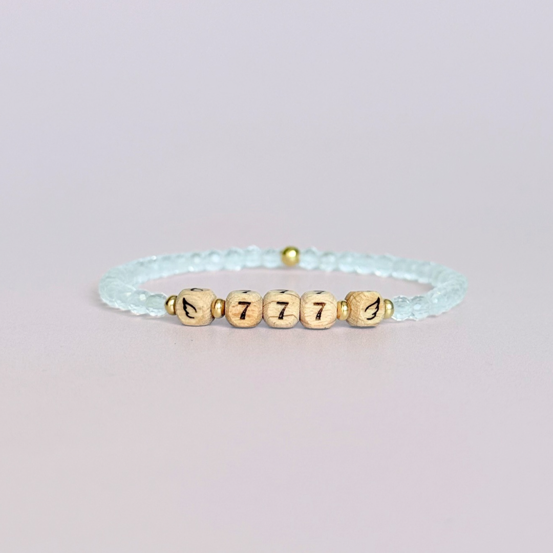 Bracelet featuring engraved wooden 777 angel number and wing beads, on the band of 4mm faceted clear quartz round crystal gemstone beads. Finished with your choice of gold vermeil, sterling silver or rose gold vermeil accent beads.