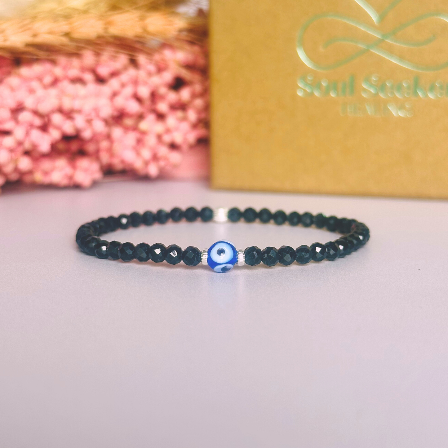 Dainty natural black tourmaline bracelet featuring ethically mined 4mm faceted gemstone beads, with a beautiful Turkish evil eye glass bead as the focal point. Choose from sterling silver or gold vermeil accent beads.