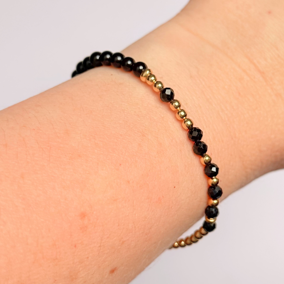 Elasticated black tourmaline crystal morse code bracelet spells out the words ‘Fuck this shit’ in a combination of 4mm round black tourmaline beads, 4mm faceted black tourmaline beads and either sterling silver or gold vermeil 3mm round beads. The words start and end at the rondelle spacer beads.