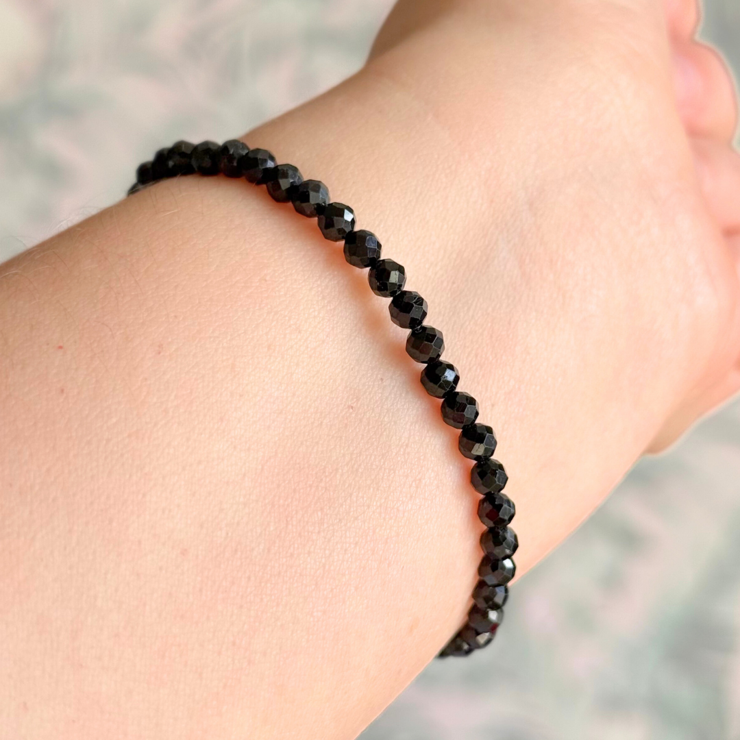 Essential oil diffuser bracelet featuring black lava rock tube bead on the band of 4mm faceted black tourmaline beads. Finished with your choice of sterling silver or gold vermeil accent beads.