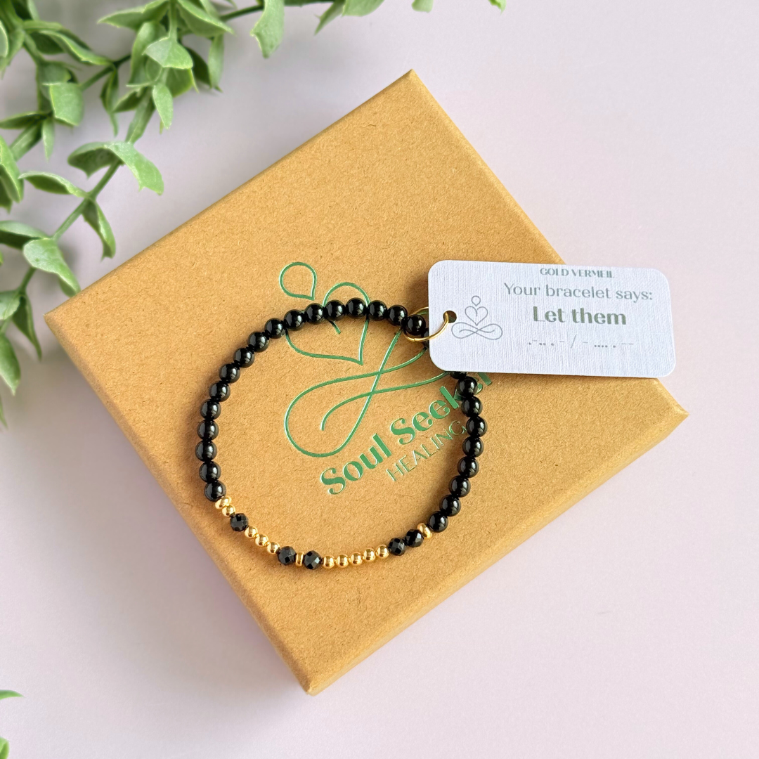Black tourmaline crystal morse code bracelet that spells out the words ‘Let them’ in a combination of 4mm round black tourmaline beads, 4mm faceted black tourmaline beads and either sterling silver or gold vermeil 3mm round beads. The words start and end at the rondelle spacer beads.