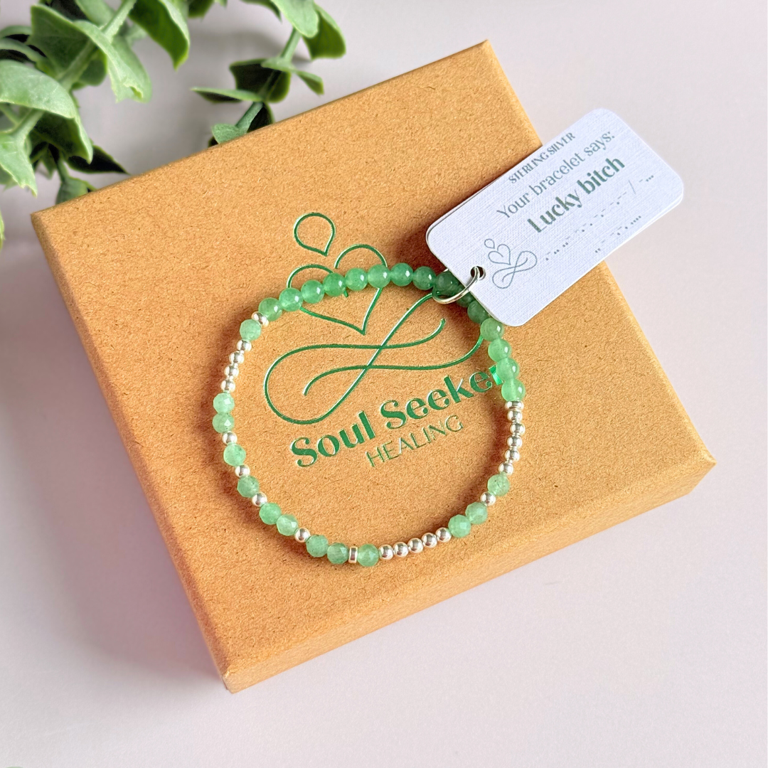 Elasticated green aventurine crystal morse code bracelet spells out the words ‘Lucky bitch’ in a combination of 4mm round green aventurine beads, 4mm faceted green aventurine beads and either sterling silver or gold vermeil 3mm round beads. The words start and end at the rondelle spacer beads.