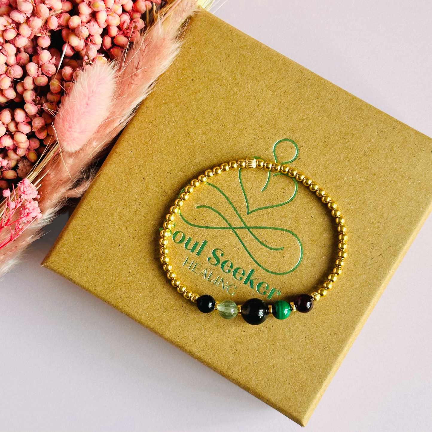 This gold vermeil Capricorn bracelet is made with a selection of five healing crystals all believed to resonate with the Capricorn zodiac sign. The central bead is 8mm, the other four are 6mm. On an elasticated band of 3mm gold vermeil beads with corrugated accent beads. Featuring garnet, malachite, fluorite, smoky quartz and black tourmaline.