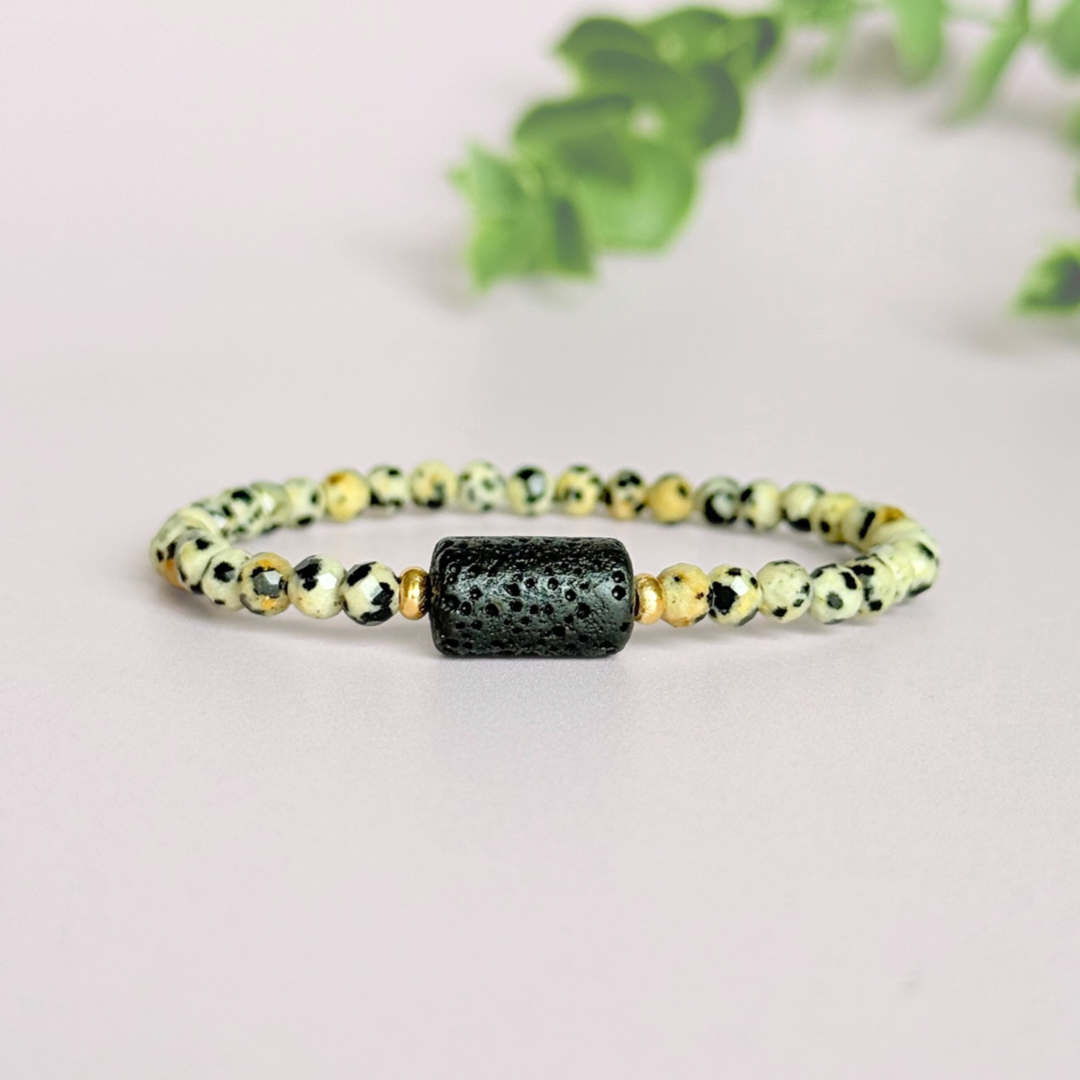 Essential oil diffuser bracelet featuring black lava rock tube bead on the band of 4mm faceted dalmatian jasper beads. Finished with your choice of sterling silver or gold vermeil accent beads.