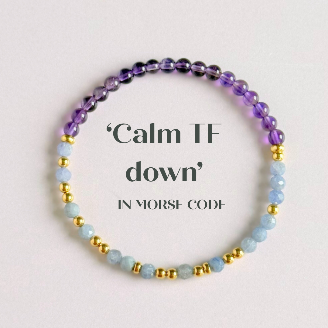 Amethyst and tanzanite elasticated stretch crystal morse code bracelet that spells out the words ‘Calm TF down’ in a combination of 4mm round amethyst beads, 4mm faceted tanzanite beads and either sterling silver or gold vermeil 3mm round beads. The words start and end at the rondelle spacer beads.