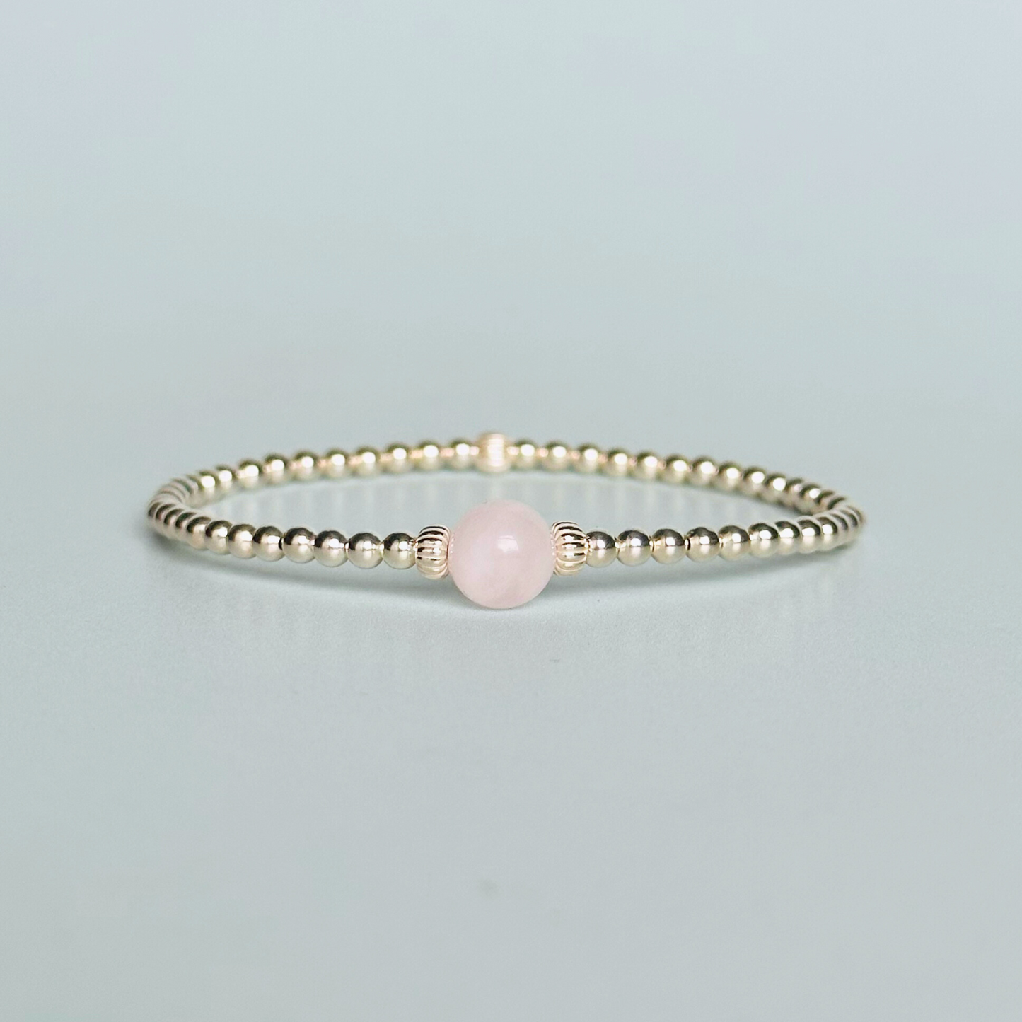 sterling silver rose quartz bracelet features an ethically mined 8mm rose quartz bead, flanked by corrugated rondelle beads on a band of 3mm sterling silver beads. A bracelet to promote self love and self-confidence.