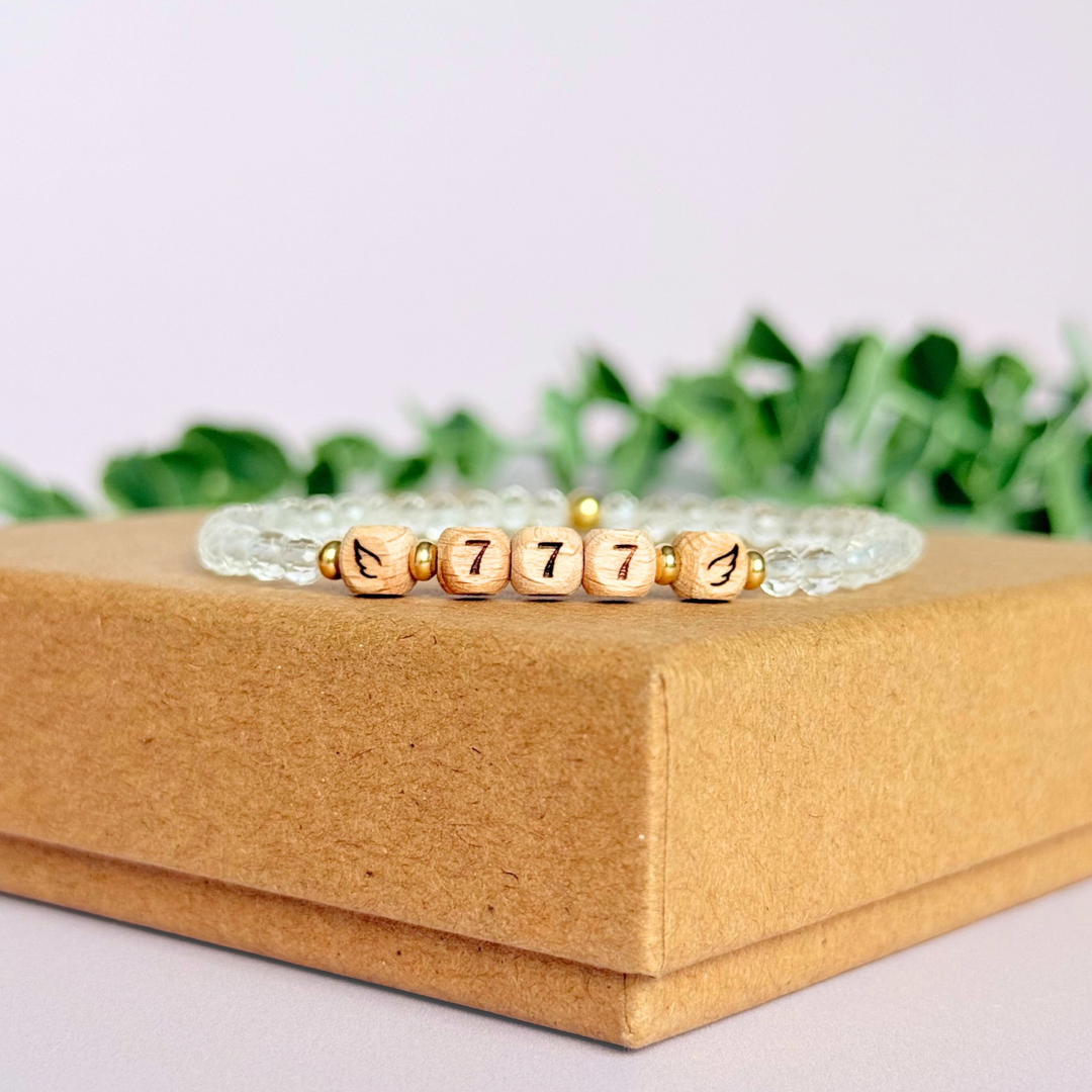 Bracelet featuring engraved wooden 777 angel number and wing beads, on the band of 4mm faceted clear quartz round crystal gemstone beads. Finished with your choice of gold vermeil, sterling silver or rose gold vermeil accent beads.