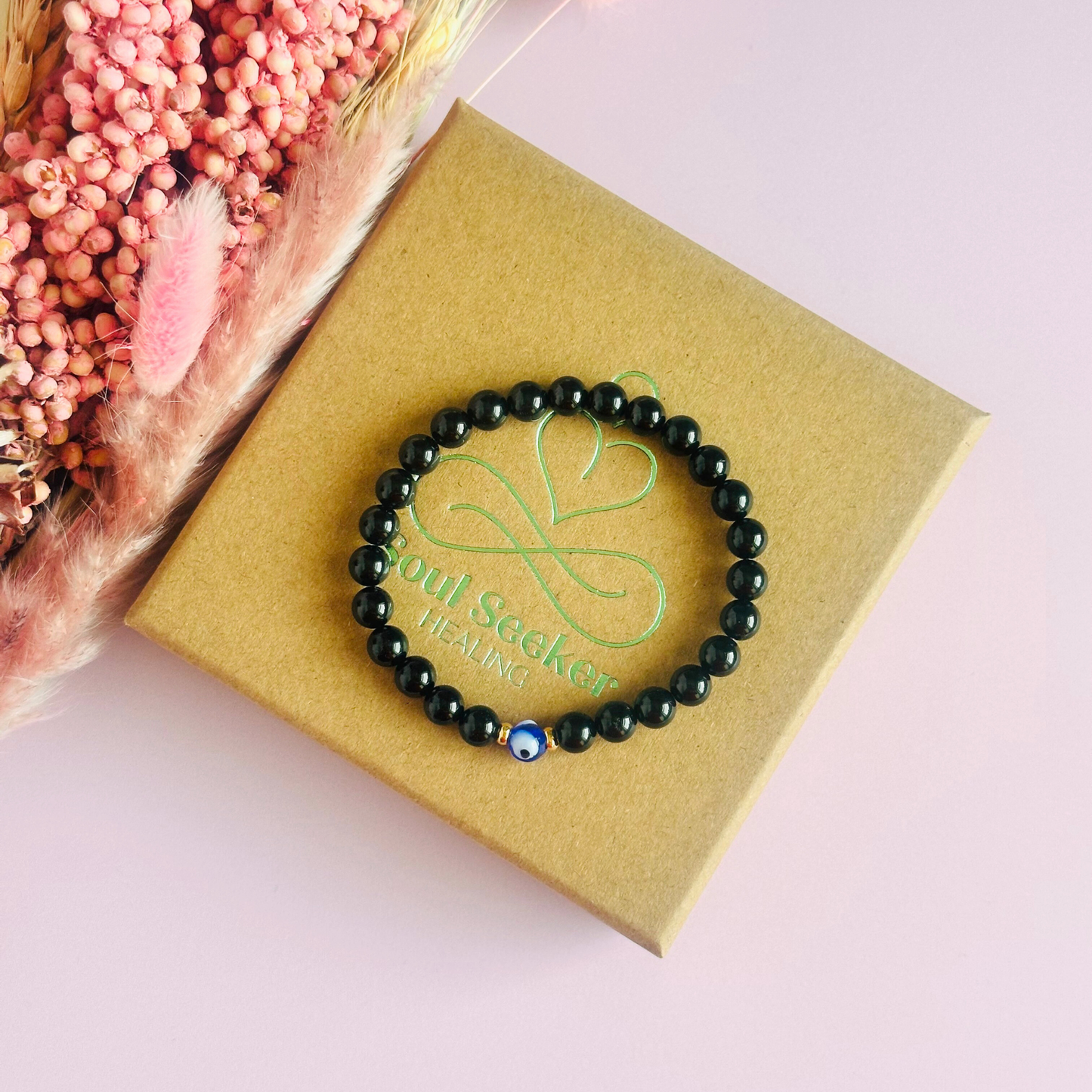 Natural black tourmaline bracelet featuring ethically mined smooth 6mm round beads with a beautiful blue Turkish evil eye glass bead as the focal point. Finished with gold vermeil or sterling silver accent beads.