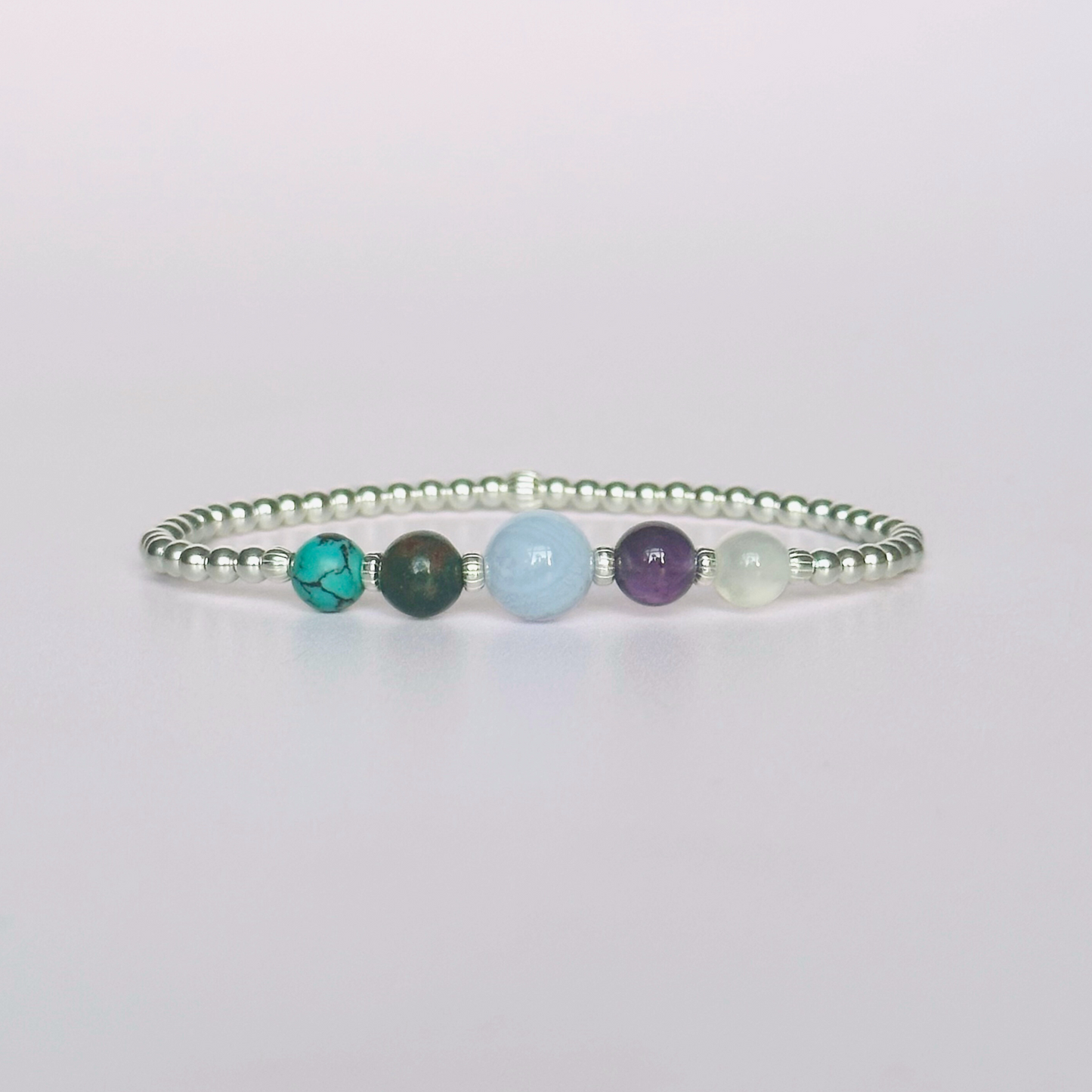 This sterling silver Pisces bracelet is made with a selection of five healing crystals all believed to resonate with the Pisces zodiac sign. The central bead is 8mm, the other four are 6mm. On an elasticated band of 3mm sterling silver beads with corrugated accent beads. Featuring turquoise, bloodstone, blue lace agate, amethyst and selenite.