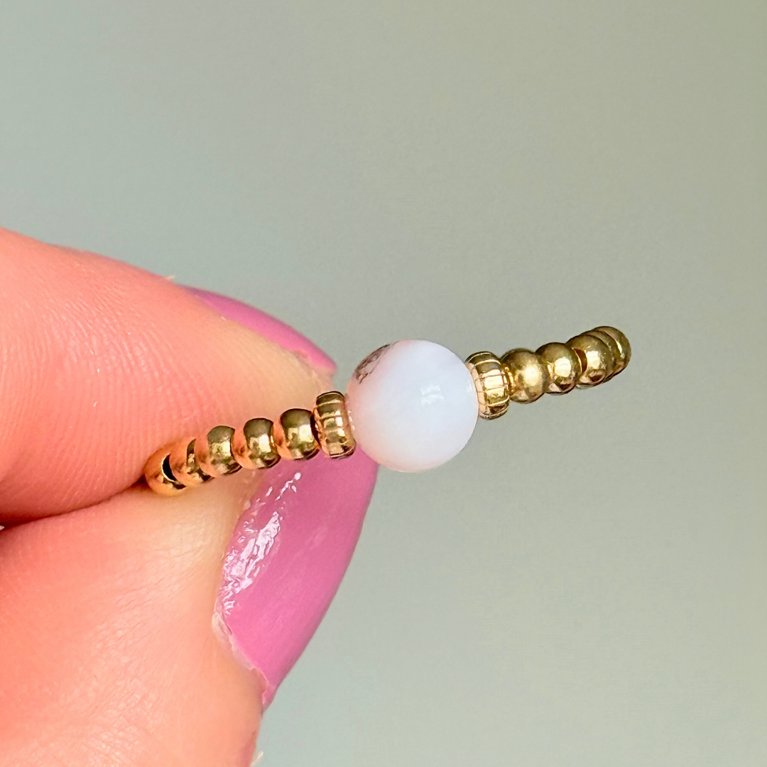 Gold vermeil pink opal October birthstone ring featuring a 6mm smooth, round pink opal bead on a band of 2.5mm gold vermeil ball beads. Elasticated for comfort.