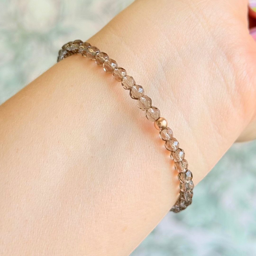 Bracelet featuring engraved wooden 999 angel number and wing beads, on the band of 4mm faceted smoky quartz round crystal gemstone beads. Finished with your choice of gold vermeil, sterling silver or rose gold vermeil accent beads.