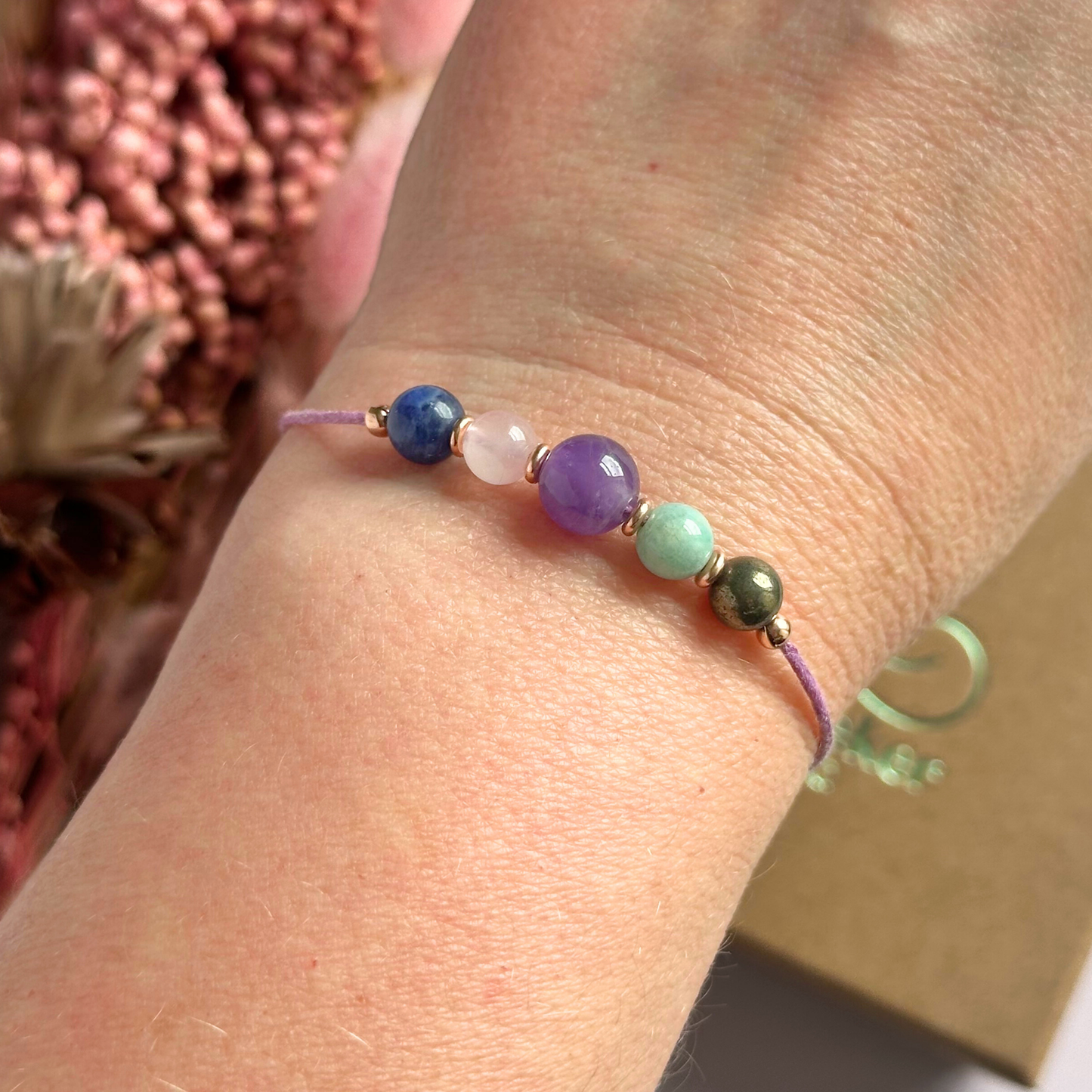 Eco-friendly, waxed cotton cord crystal healing bracelet featuring five crystals each believed to help deal with anxiety. Includes pyrite, amazonite, amethyst, rose quartz and sodalite. Adjustable as it fastens with a sliding macramé clasp. Choose from either sterling silver, gold vermeil or rose gold vermeil accent beads.