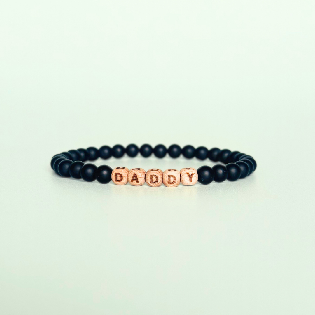 Men’s crystal bracelet with 6mm frosted black onyx gemstone crystal beads and laser engraved wooden letter beads featuring the word daddy or can also be made with any other words or letters.