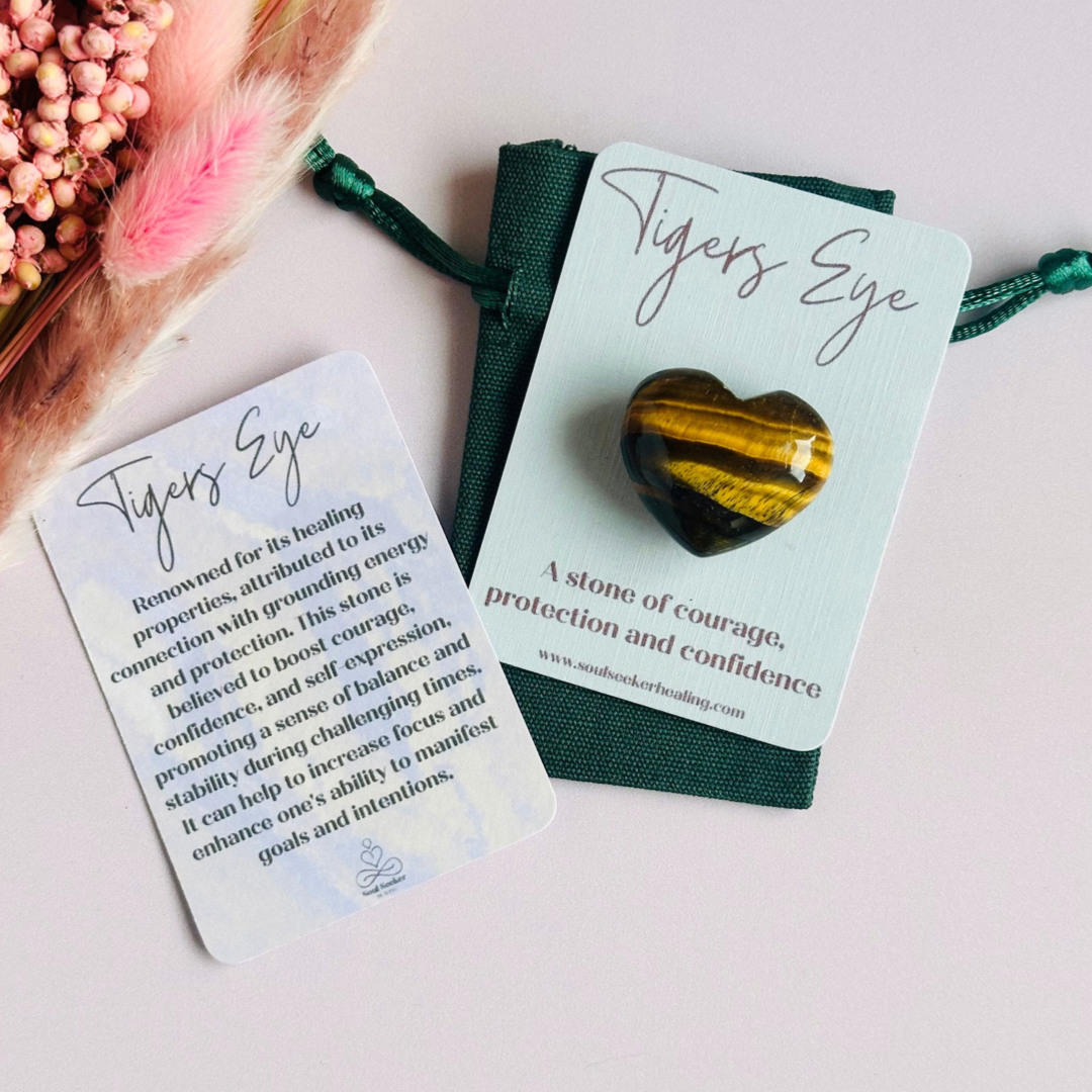 An ethically mined tigers eye heart, presented on an eco-friendly textured card with the words 'A stone of courage, protection and confidence. This heart shaped tigers eye crystal measures approximately 25mm x 25mm, making it an ideal size to carry with you wherever you go or to display in your sacred space. A cotton bag is included to keep it safe.