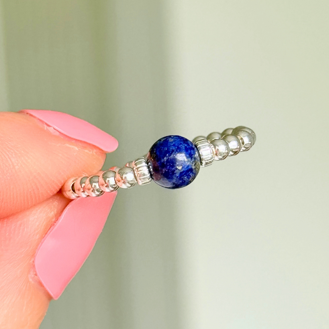 Sterling silver beaded ring featuring a 6mm lapis lazuli round bead, flanked by sterling silver corrugated beads. Elasticated for comfort.