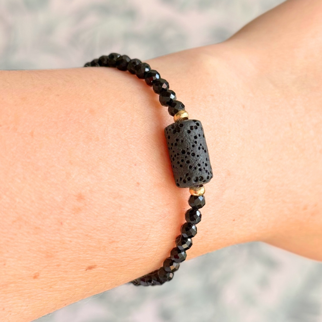 Essential oil diffuser bracelet featuring black lava rock tube bead on the band of 4mm faceted black tourmaline beads. Finished with your choice of sterling silver or gold vermeil accent beads.