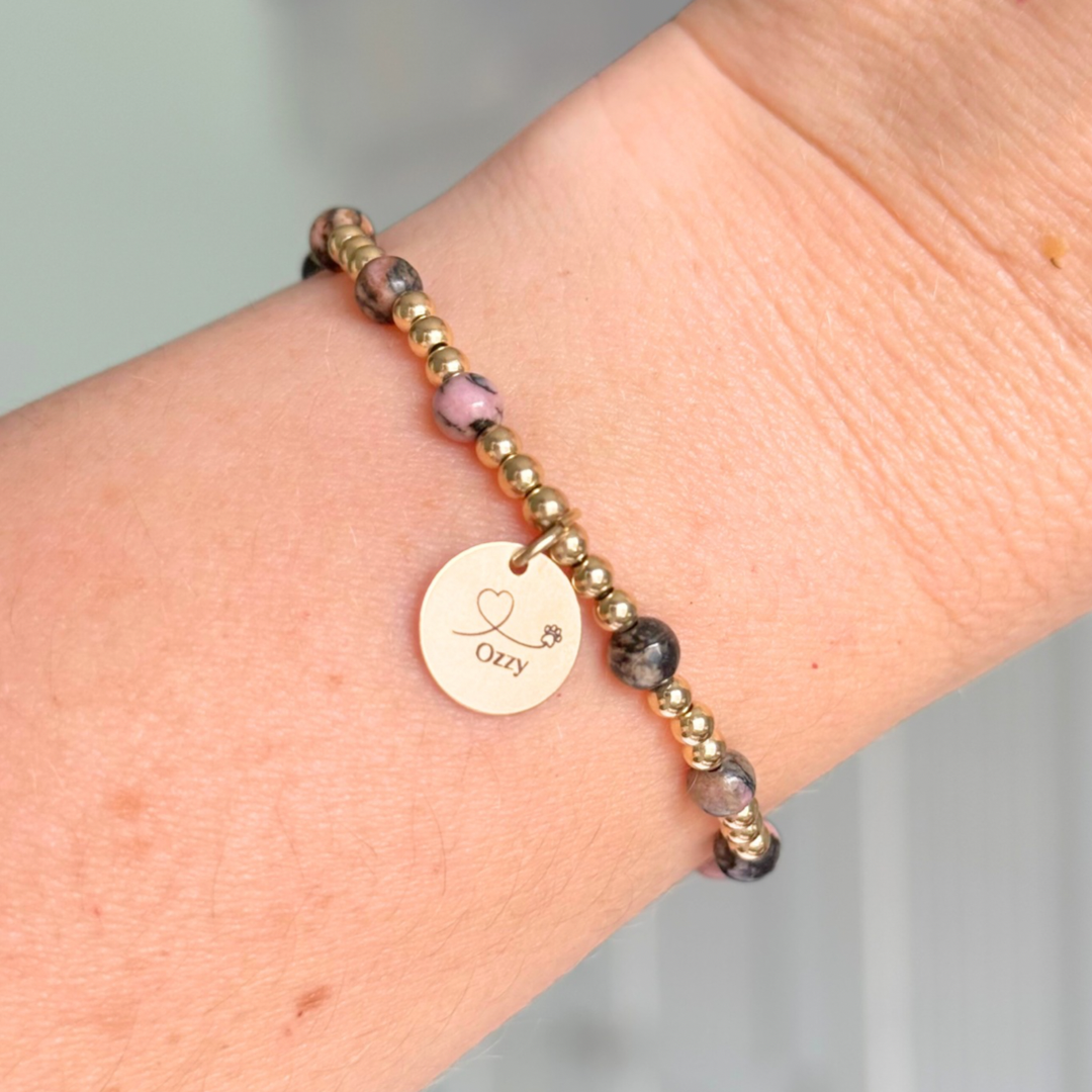 Gold filled bracelet featuring ethically mined 4mm rhodonite crystal beads, separated by 3mm gold filled beads. It features an 11mm gold filled disc charm, which is engraved with a love heart and paw design, which can be personalised with your pet's name. The reverse of the charm says 'Forever in your heart x', although this side can also be personalised with your own words.