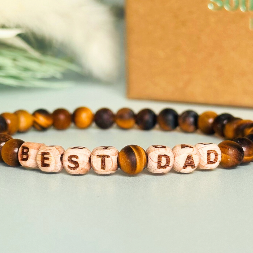 Men’s crystal bracelet with 6mm frosted tigers eye gemstone crystal beads and laser engraved wooden letter beads featuring the words best dad or can also be made with any other words or letters.