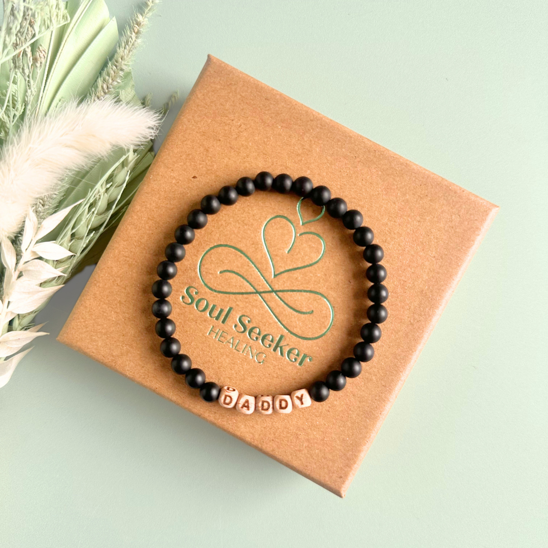 Men’s crystal bracelet with 6mm frosted black onyx gemstone crystal beads and laser engraved wooden letter beads featuring the word daddy or can also be made with any other words or letters.