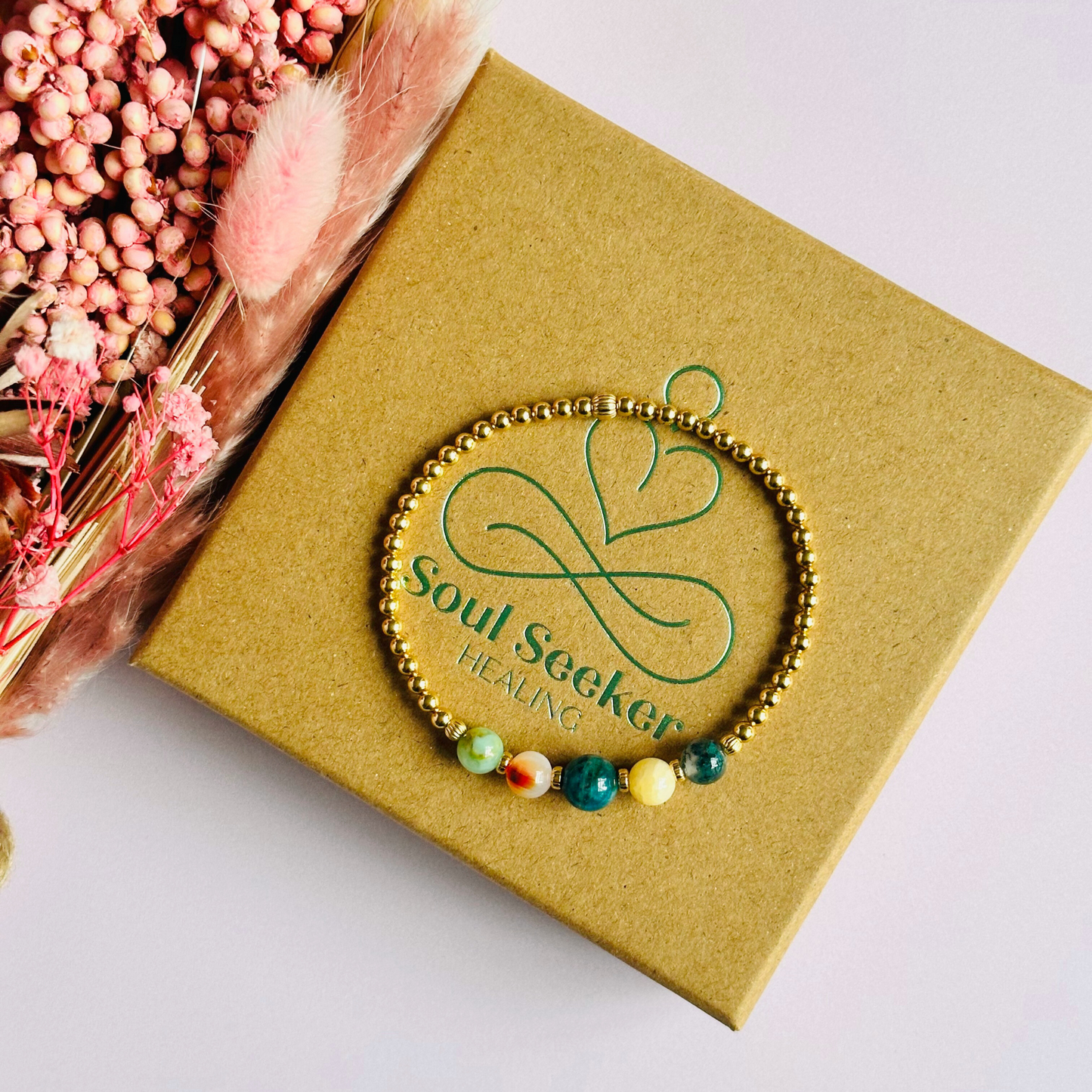 This gold vermeil Gemini bracelet is made with a selection of five healing crystals all believed to resonate with the Gemini zodiac sign. The central bead is 8mm, the other four are 6mm. On an elasticated band of 3mm gold vermeil beads with corrugated accent beads. Featuring chrysocolla, dendritic agate, apatite, yellow calcite and moss agate.