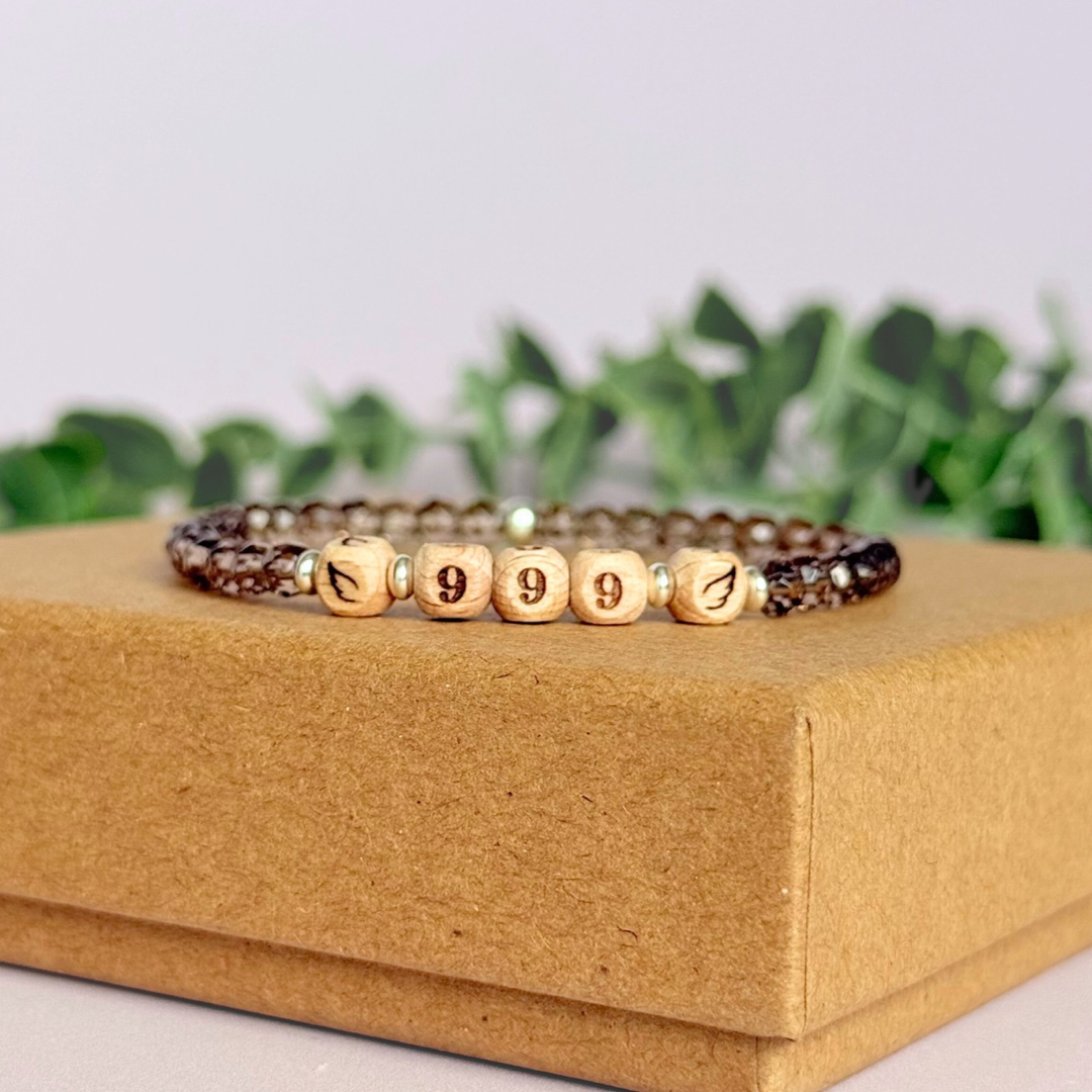 Bracelet featuring engraved wooden 999 angel number and wing beads, on the band of 4mm faceted smoky quartz round crystal gemstone beads. Finished with your choice of gold vermeil, sterling silver or rose gold vermeil accent beads.