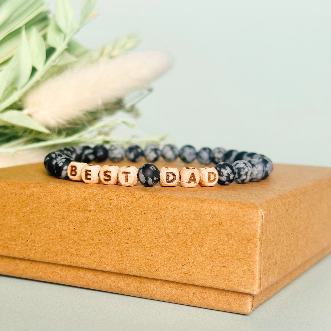 Men’s crystal bracelet with 6mm frosted snowflake obsidian gemstone crystal beads and laser engraved wooden letter beads featuring the word best dad or can also be made with any other words or letters.