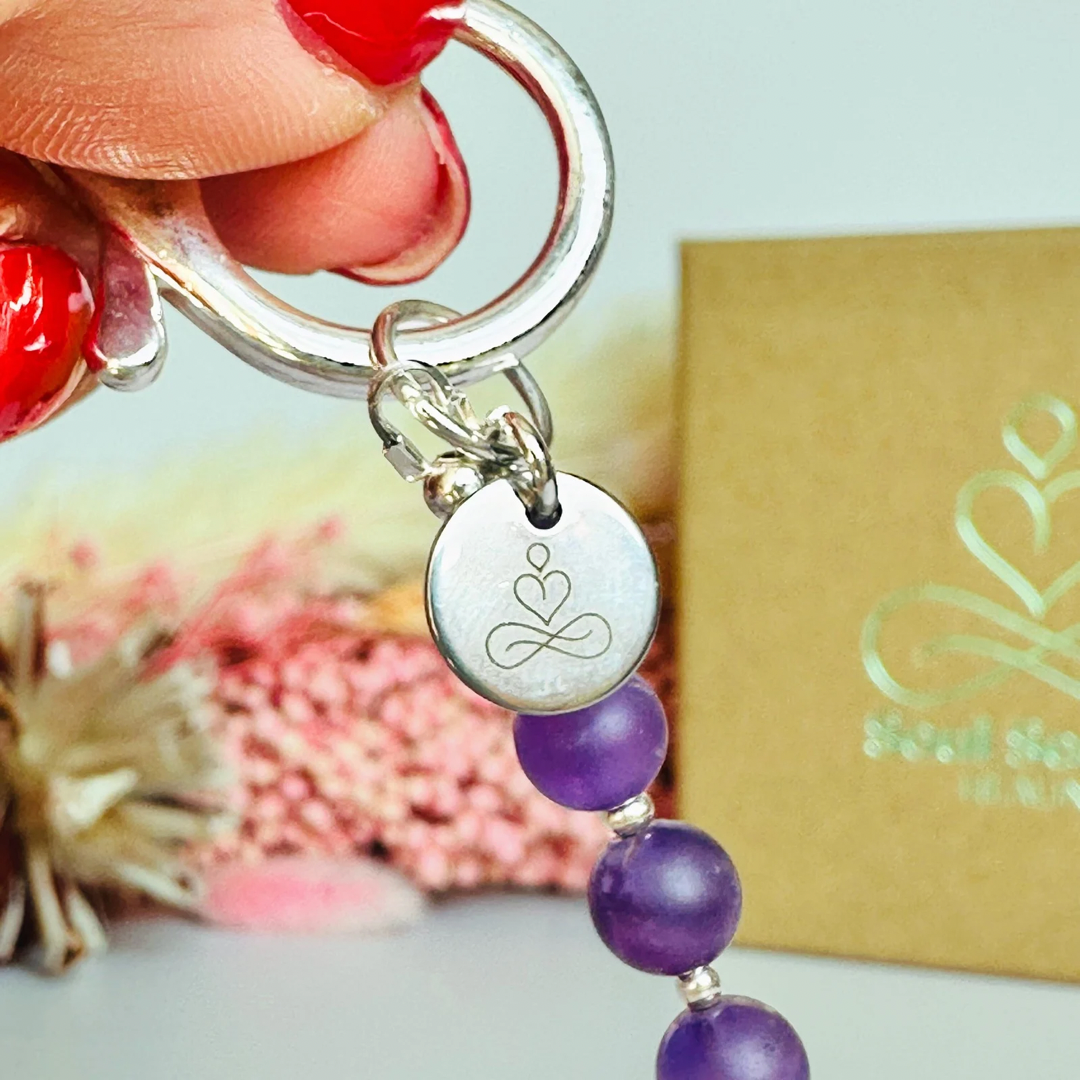 Frosted amethyst breath work beads on a silver keychain/bag charm. For the 4-7-8 counted breathing method.