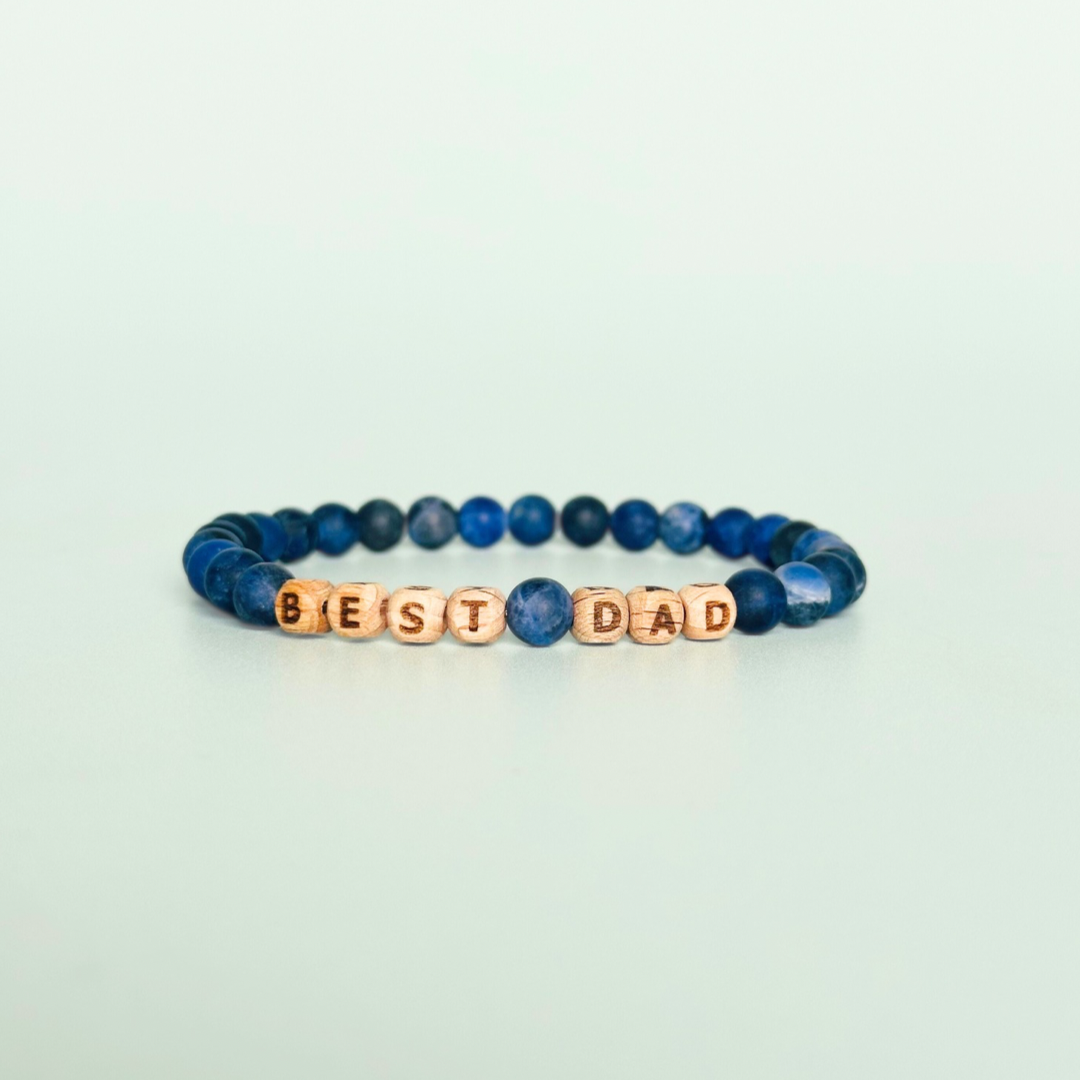 Men’s crystal bracelet with 6mm frosted sodalite gemstone crystal beads and laser engraved wooden letter beads featuring the words best dad or can also be made with any other words or letters.