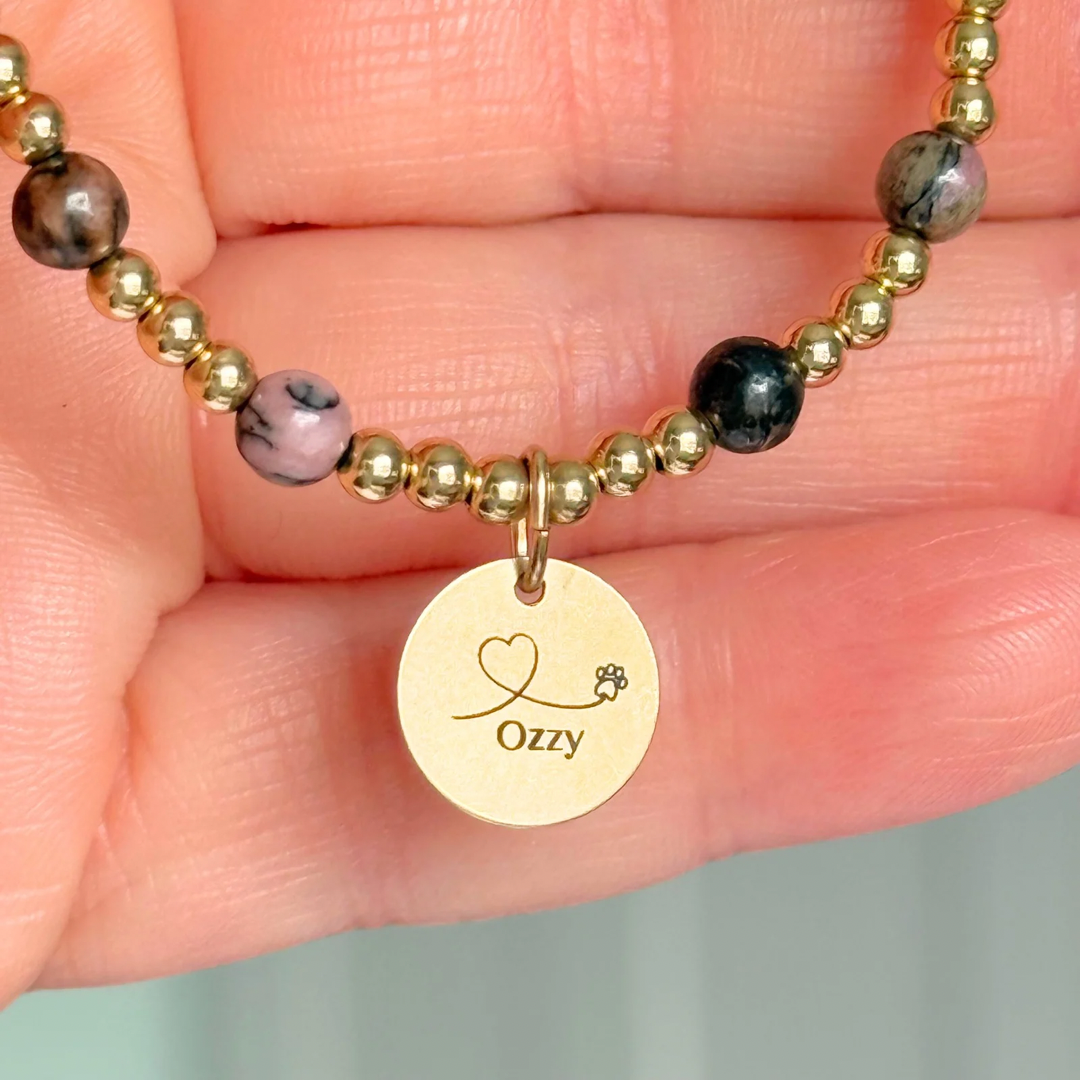 Gold filled bracelet featuring ethically mined 4mm rhodonite crystal beads, separated by 3mm gold filled beads. It features an 11mm gold filled disc charm, which is engraved with a love heart and paw design, which can be personalised with your pet's name. The reverse of the charm says 'Forever in your heart x', although this side can also be personalised with your own words.