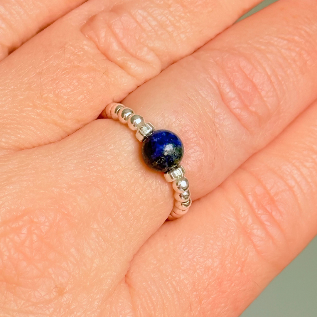 Sterling silver beaded ring featuring a 6mm lapis lazuli round bead, flanked by sterling silver corrugated beads. Elasticated for comfort.