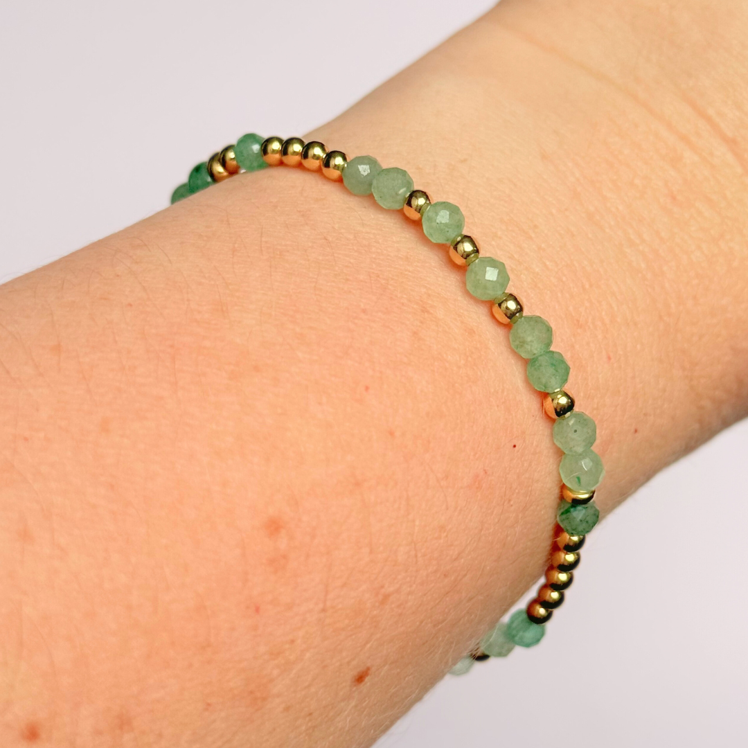 Elasticated green aventurine crystal morse code bracelet spells out the words ‘Lucky bitch’ in a combination of 4mm round green aventurine beads, 4mm faceted green aventurine beads and either sterling silver or gold vermeil 3mm round beads. The words start and end at the rondelle spacer beads.