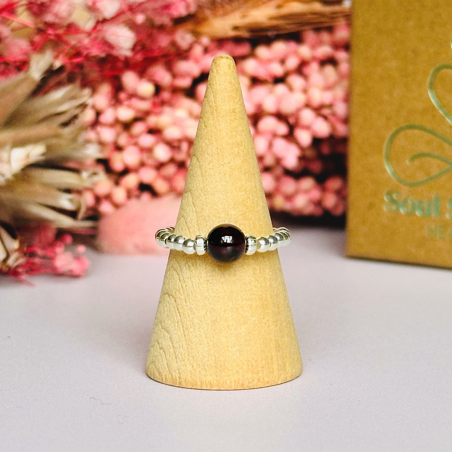 Sterling silver garnet ring featuring a 6mm smooth round garnet bead on a elasticated ring band of 2.5mm sterling silver beads.