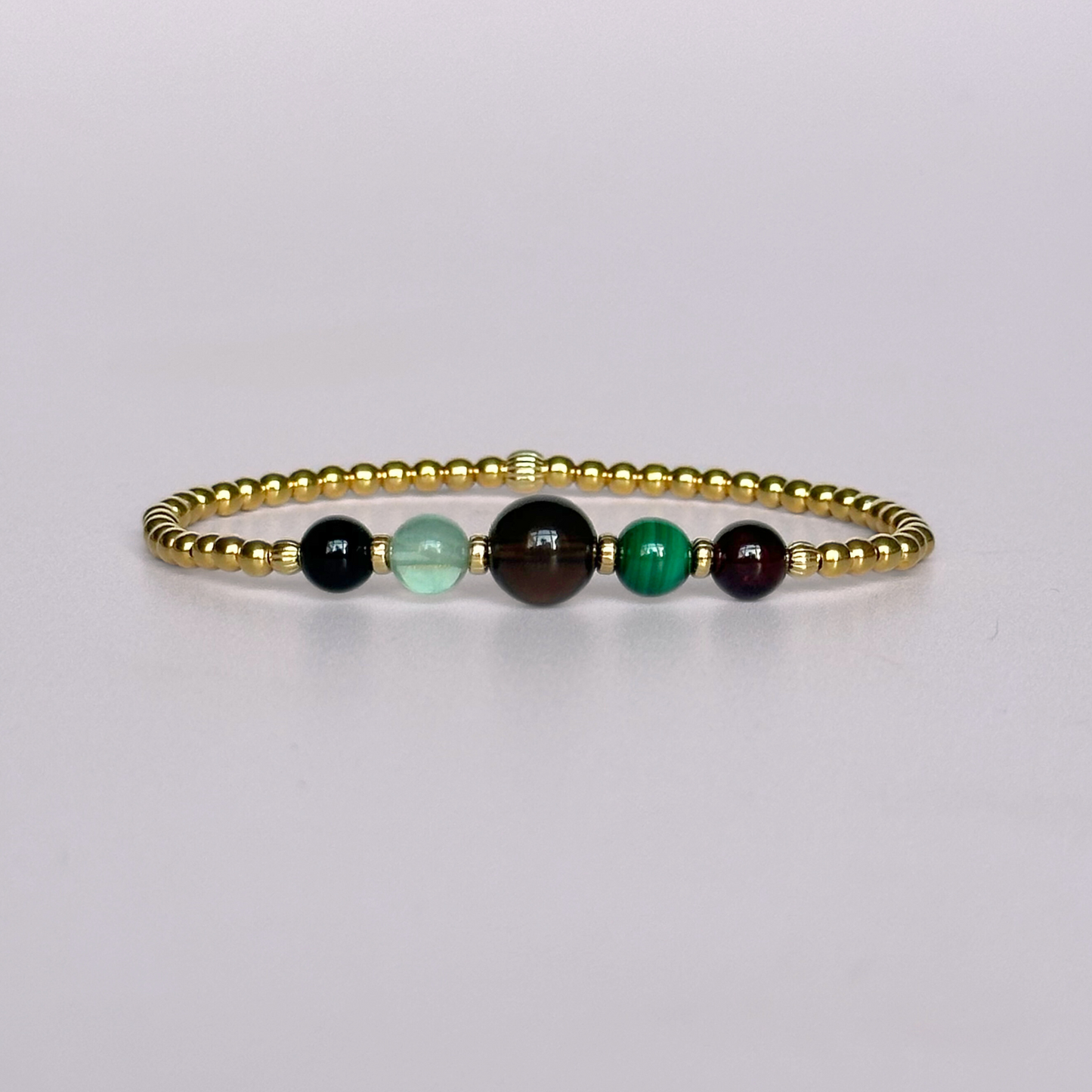This gold vermeil Capricorn bracelet is made with a selection of five healing crystals all believed to resonate with the Capricorn zodiac sign. The central bead is 8mm, the other four are 6mm. On an elasticated band of 3mm gold vermeil beads with corrugated accent beads. Featuring garnet, malachite, fluorite, smoky quartz and black tourmaline.