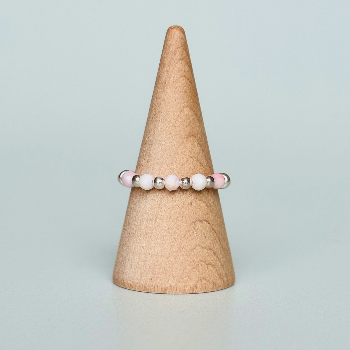 Birthstone ring featuring 5 3mm. Faceted Peruvian pink opal beads on an elasticated band of 3mm sterling silver round beads, pink opal is an October birth stone so this makes a perfect October birthday gift.