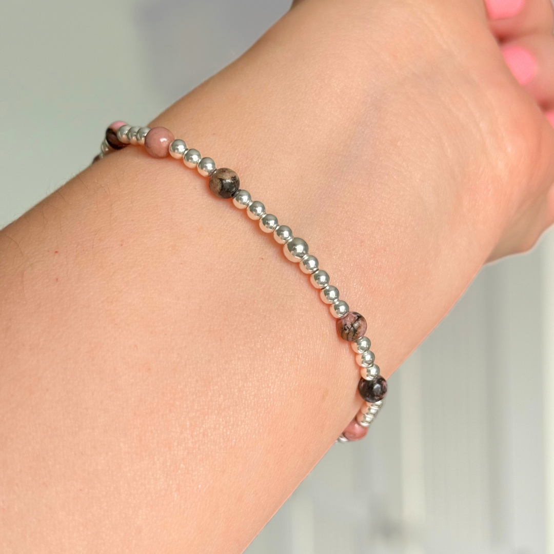 Sterling silver bracelet featuring ethically mined 4mm rhodonite crystal beads, separated by 3mm sterling silver beads. It features an 11mm sterling silver disc charm, which is engraved with a love heart and paw design, which can be personalised with your pet's name. The reverse of the charm says 'Forever in your heart x', although this side can also be personalised with your own words.