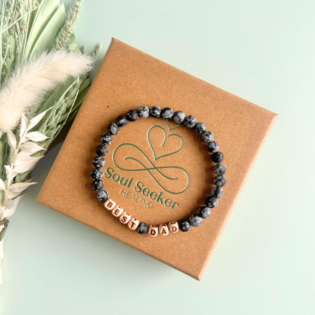 Men’s crystal bracelet with 6mm frosted snowflake obsidian gemstone crystal beads and laser engraved wooden letter beads featuring the word best dad or can also be made with any other words or letters.