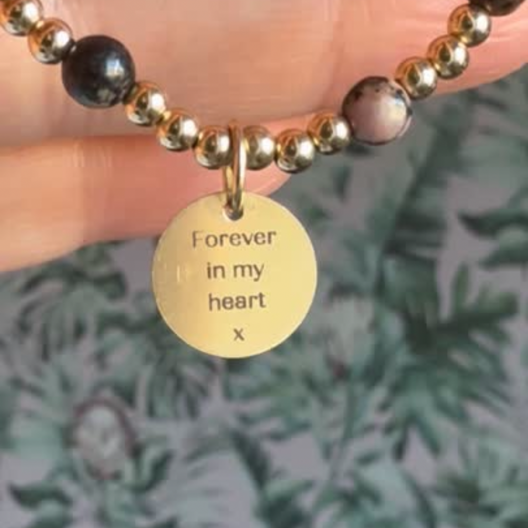 Gold filled bracelet featuring ethically mined 4mm rhodonite crystal beads, separated by 3mm gold filled beads. It features an 11mm gold filled disc charm, which is engraved with a love heart and paw design, which can be personalised with your pet's name. The reverse of the charm says 'Forever in your heart x', although this side can also be personalised with your own words.