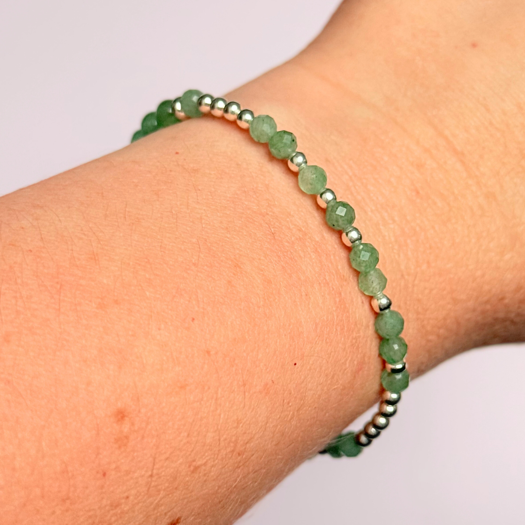 Elasticated green aventurine crystal morse code bracelet spells out the words ‘Lucky bitch’ in a combination of 4mm round green aventurine beads, 4mm faceted green aventurine beads and either sterling silver or gold vermeil 3mm round beads. The words start and end at the rondelle spacer beads.