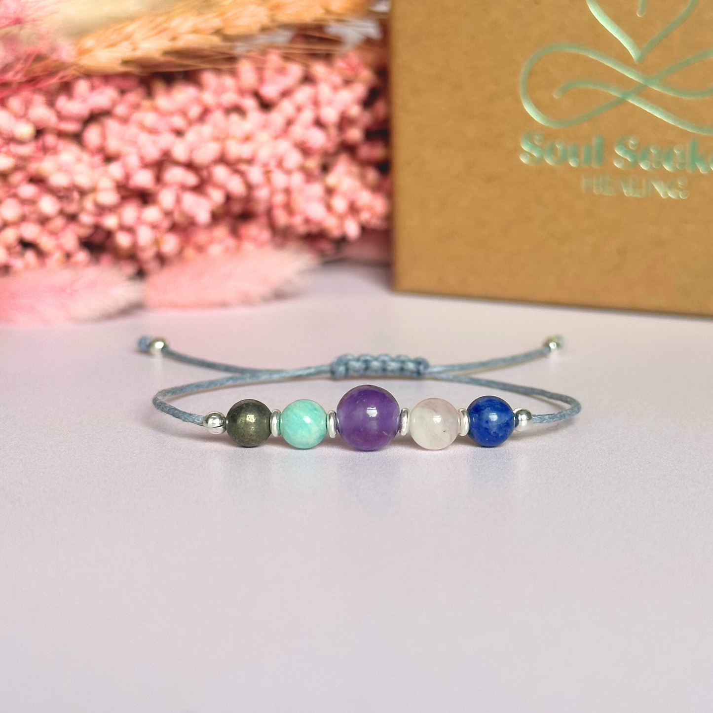Eco-friendly, waxed cotton cord crystal healing bracelet featuring five crystals each believed to help deal with anxiety. Includes pyrite, amazonite, amethyst, rose quartz and sodalite. Adjustable as it fastens with a sliding macramé clasp. Choose from either sterling silver, gold vermeil or rose gold vermeil accent beads.