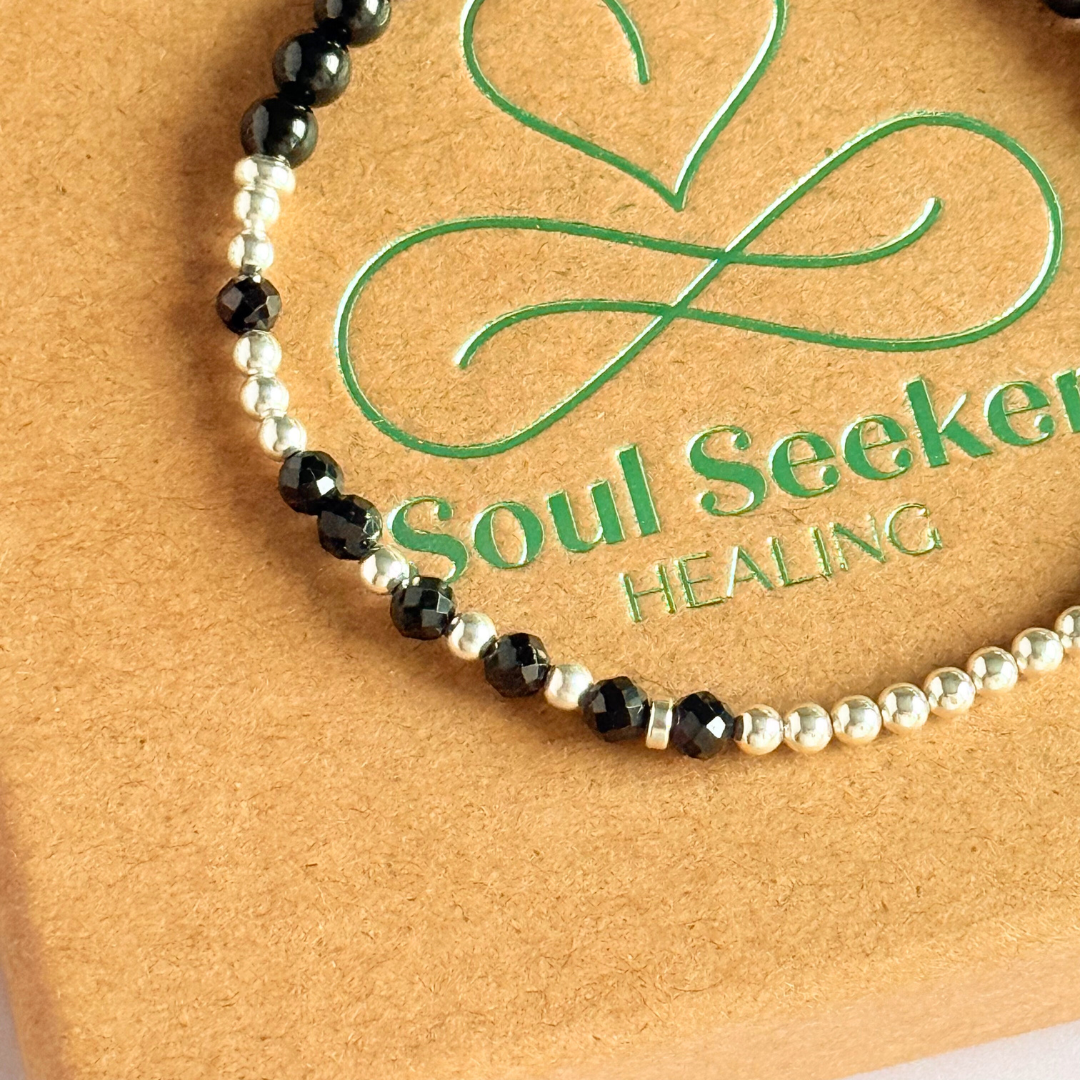 Elasticated black tourmaline crystal morse code bracelet spells out the words ‘Fuck this shit’ in a combination of 4mm round black tourmaline beads, 4mm faceted black tourmaline beads and either sterling silver or gold vermeil 3mm round beads. The words start and end at the rondelle spacer beads.