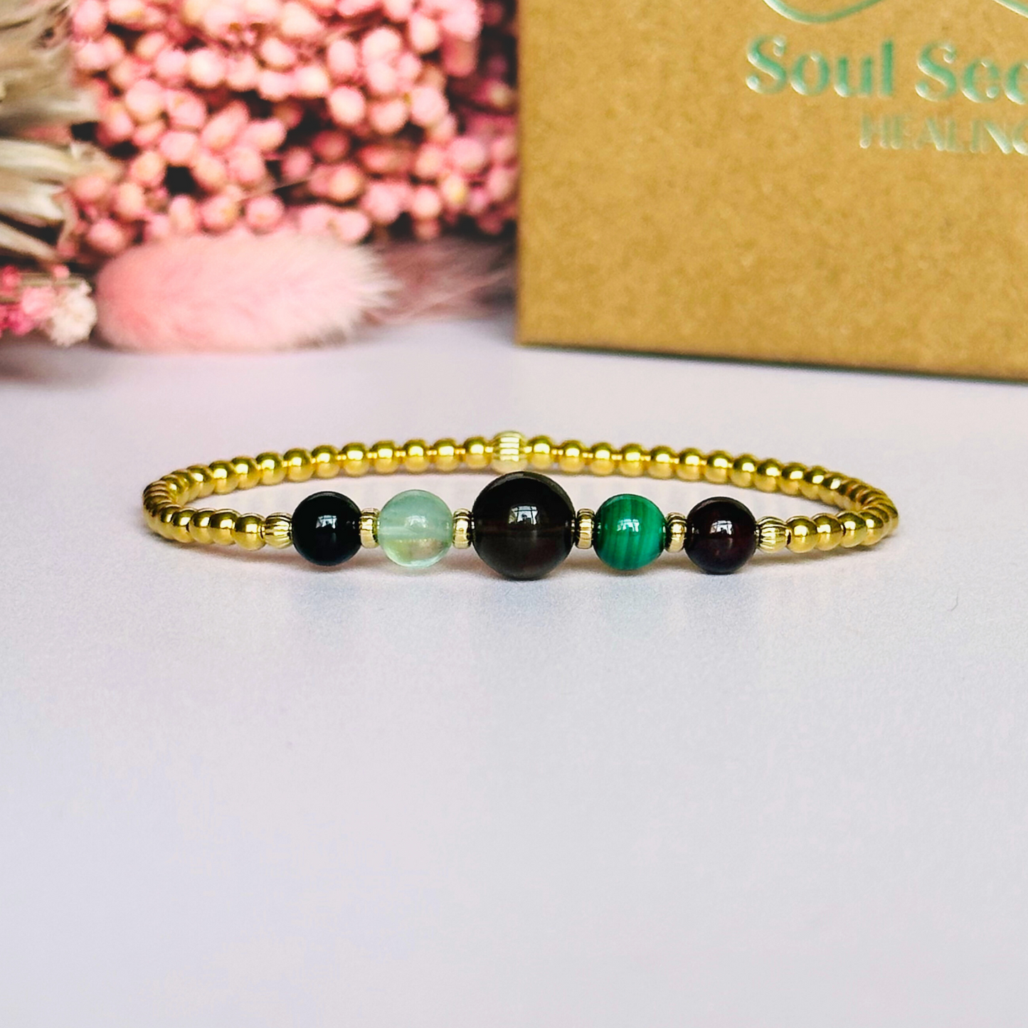This gold vermeil Capricorn bracelet is made with a selection of five healing crystals all believed to resonate with the Capricorn zodiac sign. The central bead is 8mm, the other four are 6mm. On an elasticated band of 3mm gold vermeil beads with corrugated accent beads. Featuring garnet, malachite, fluorite, smoky quartz and black tourmaline.
